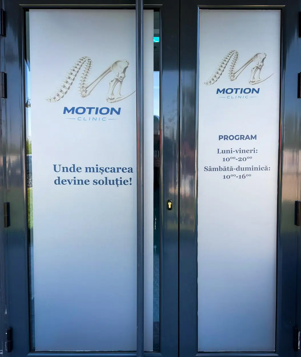 Intrarea Motion Clinic cu programul clinicii afișat