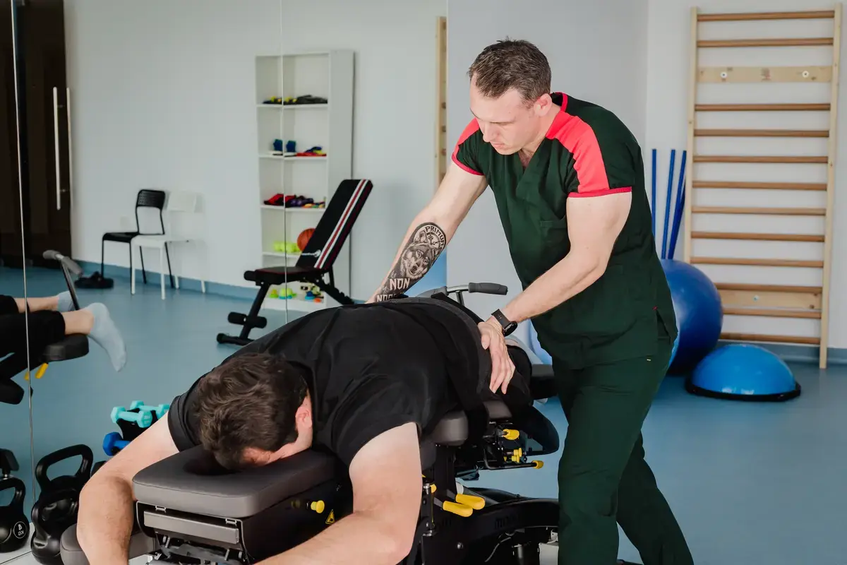 Fizioterapeut aplică tehnici manuale pe zona lombară a unui pacient așezat pe masă de tratament, în sala de kinetoterapie Motion Clinic, Snagov Plaza, Ilfov.