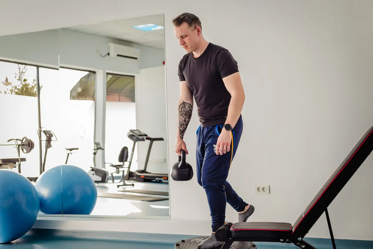 Echilibru pe plată instabilă circulară cu kettlebell — sala de kinetoterapie Motion Clinic cu oglinzi și mingi de exerciții, Snagov Plaza.