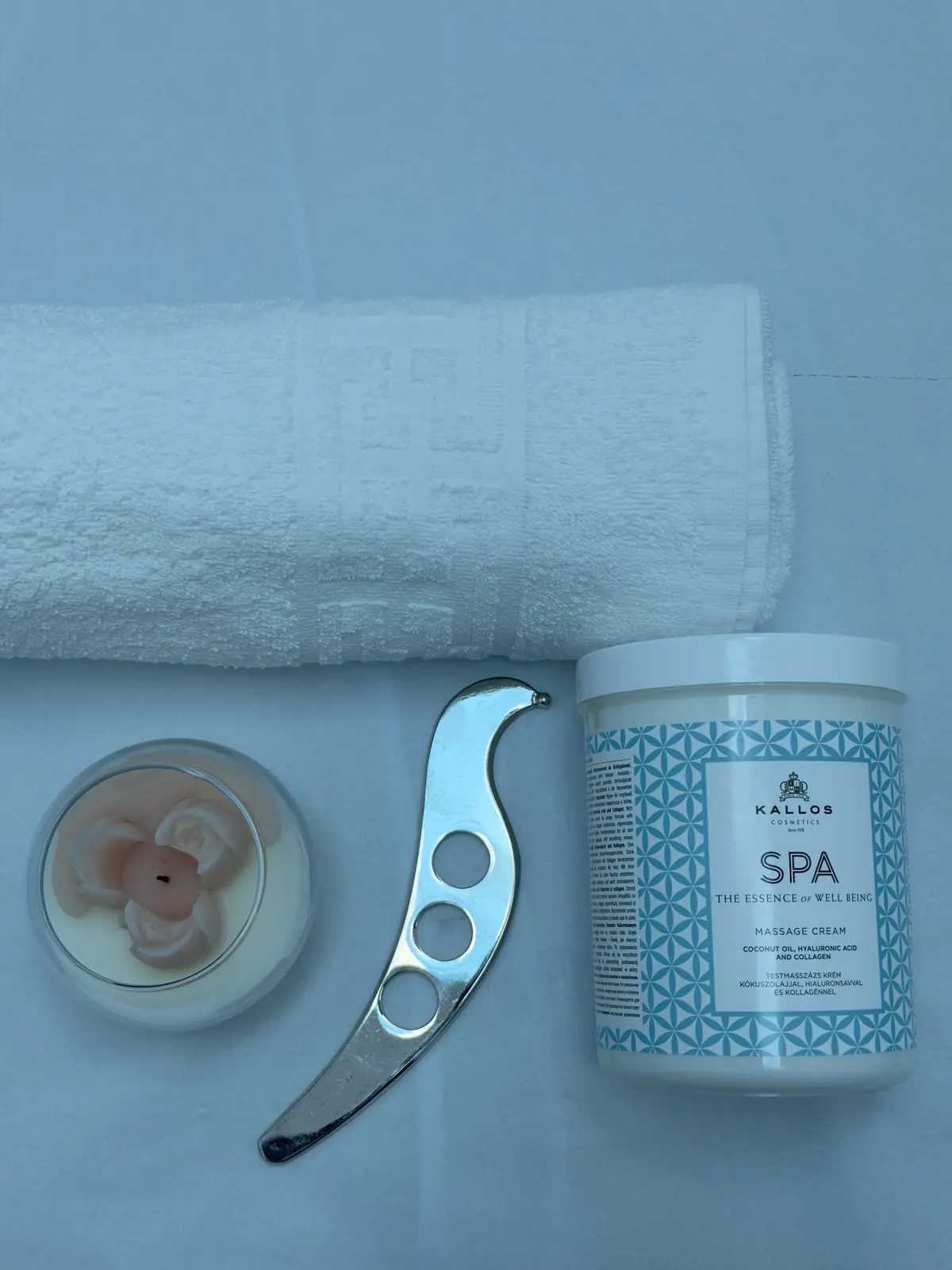 Unealtă IASTM din inox, cremă de masaj profesională și prosop alb pe masă — materiale pentru terapie manuală Motion Clinic.