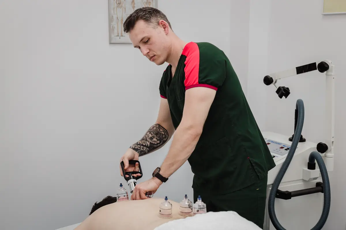 Aplicare ventuze pe spatele pacientului în prona; terapeut în uniformă Motion Clinic — tehnică manuală în cabinet, Snagov Plaza.